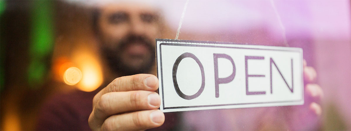 a man putting an open sign in his business window