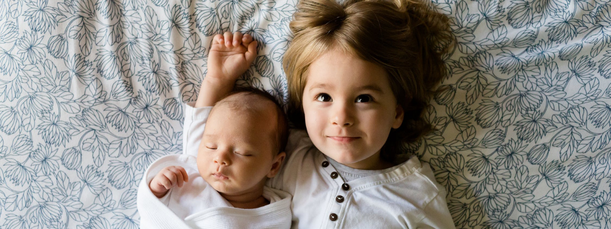 baby and toddler laying in bed