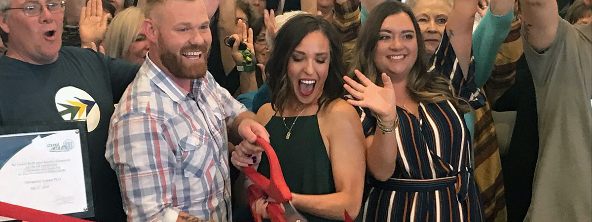 Chiropractic Essence owners cutting a red ribbon in fro