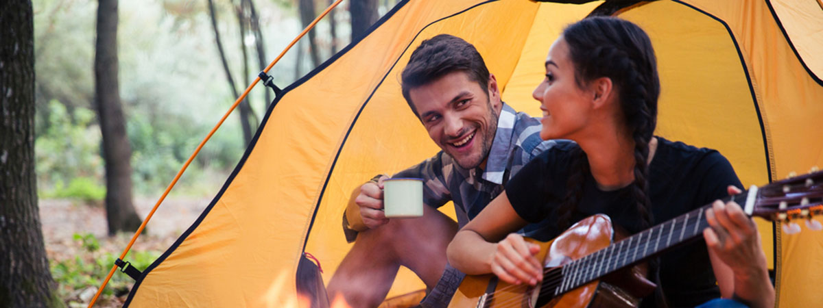 a couple sitting around a campfire in front of their te