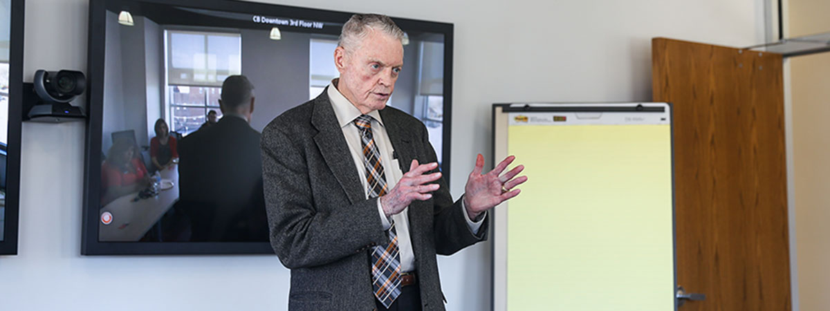 tom osborne speaks to a room of people