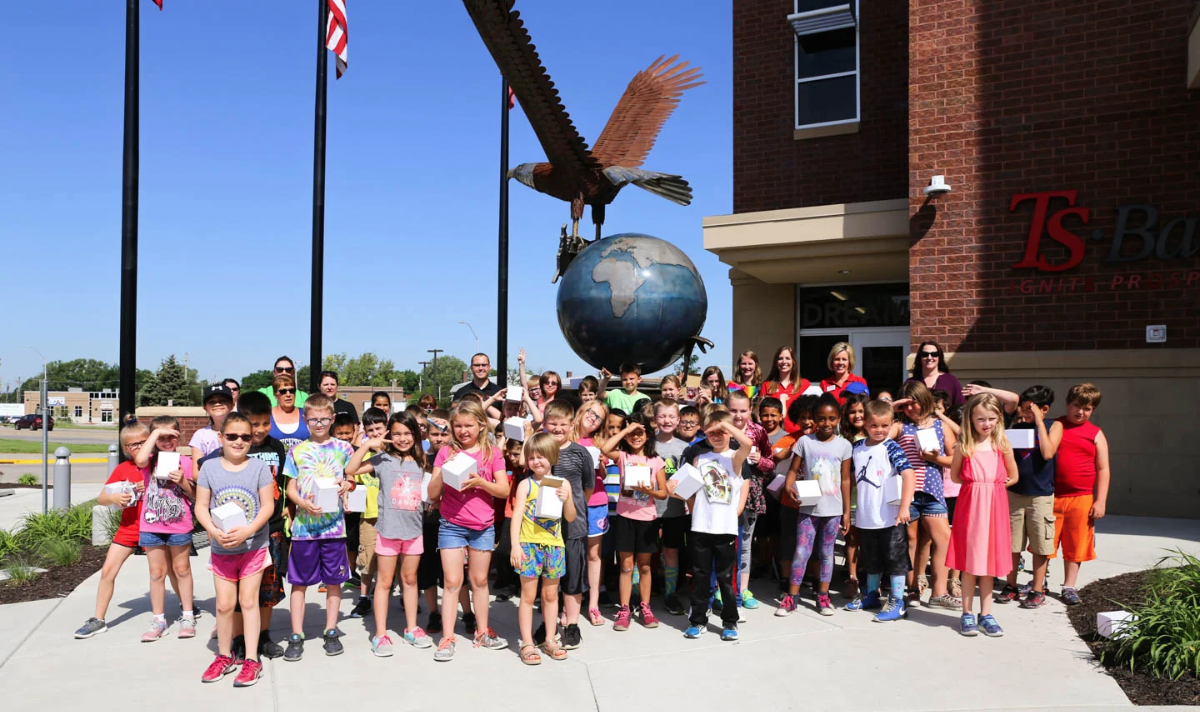 students posing in front of statue at downtown council bluffs branch