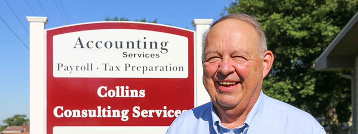norm collins standing next to his business sign outdoor