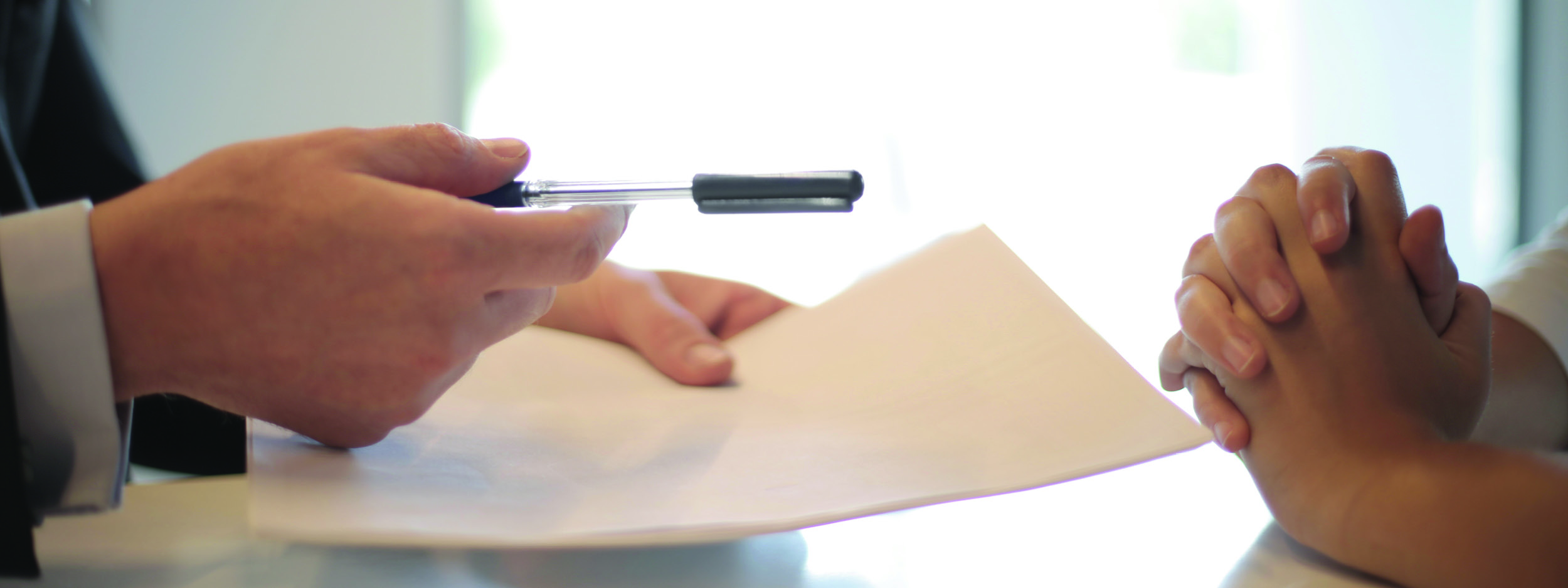 a man handing a pen to another man to sign a paper