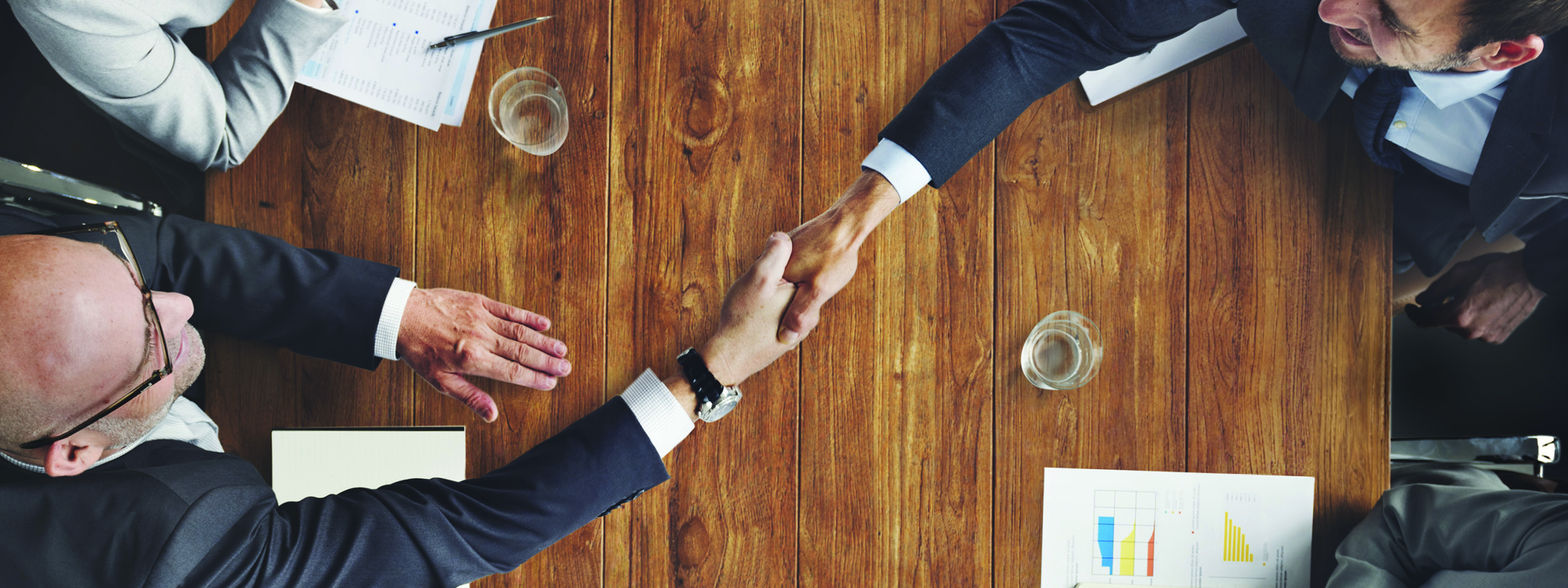 two businessmen shaking hands across a table