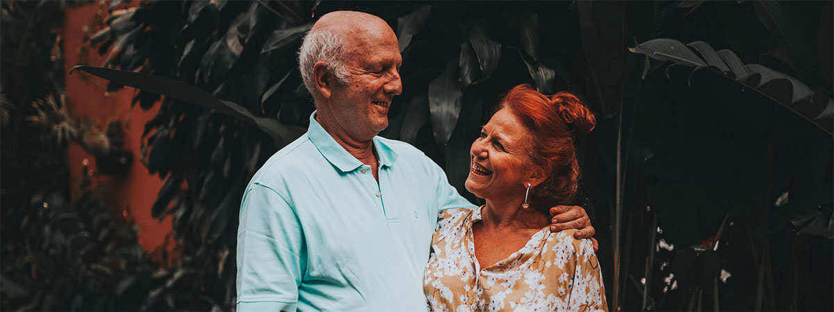 a middle aged couple standing outside smiling at one an