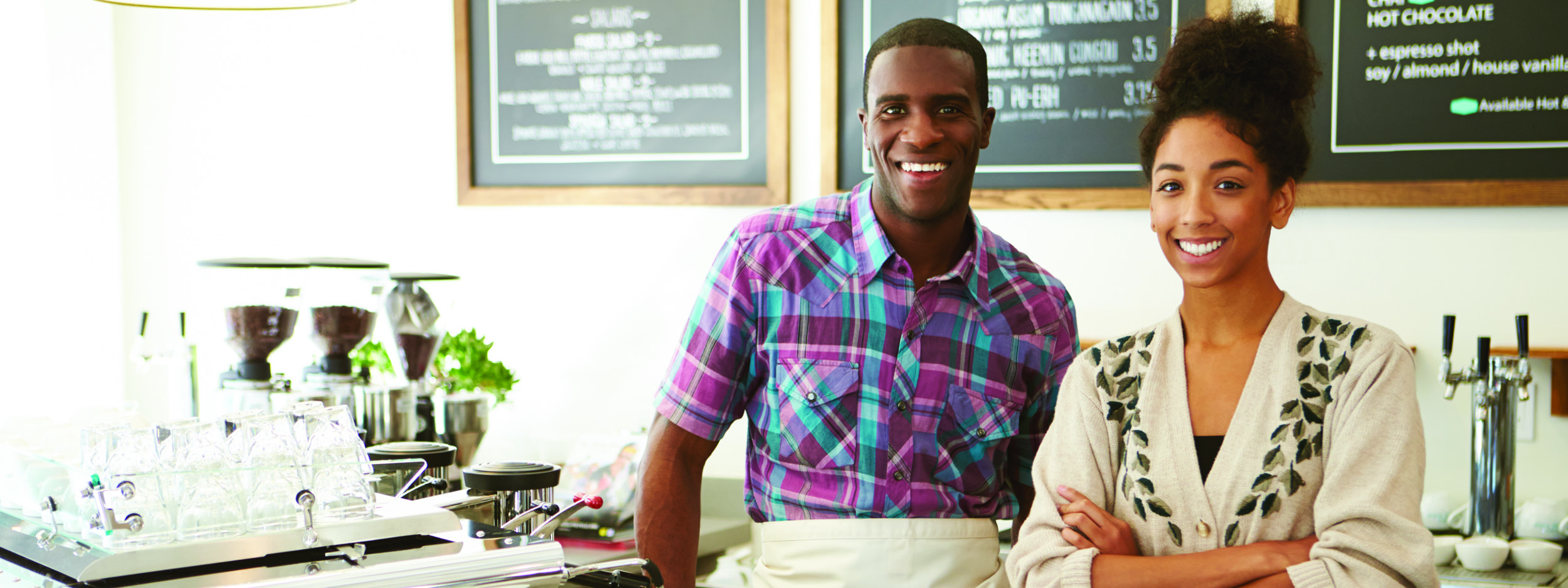 two restaurant owners smiling behind their counter