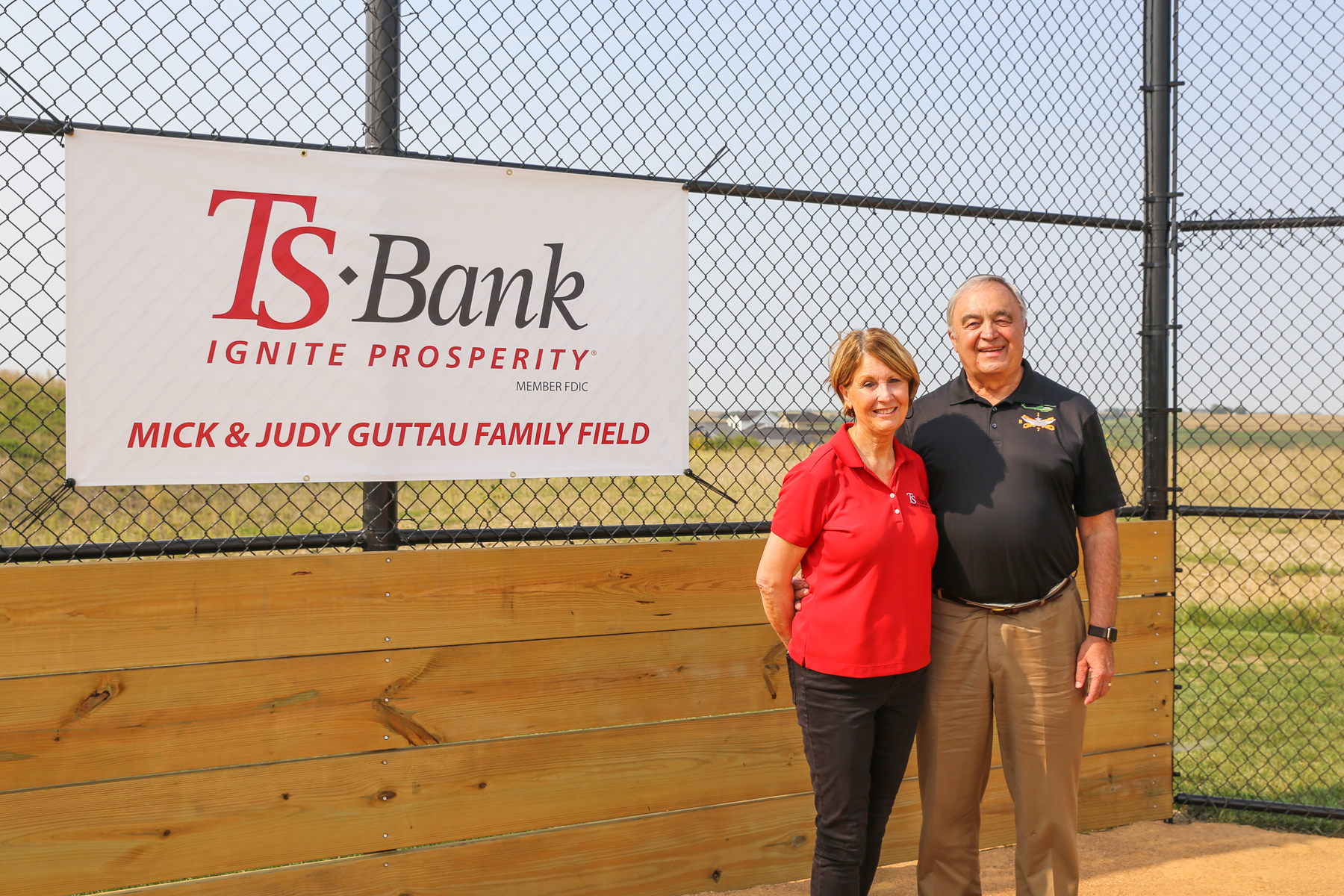 mick and judy standing by little league field sign