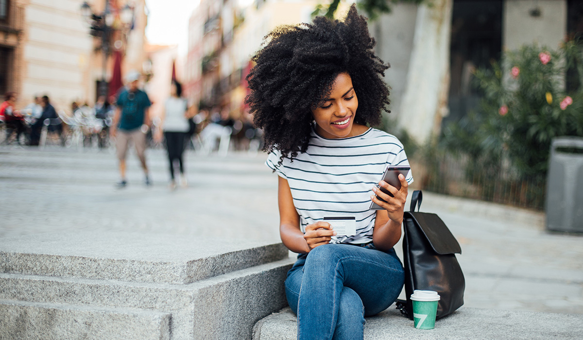 woman using her debit card to purchase something on her cell phone